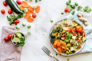 A colorful plate of high-fiber vegetables and quinoa, surrounded by fresh ingredients like cherry tomatoes, Brussels sprouts, carrots, zucchini, and herbs, promoting the benefits of fiber in your diet.